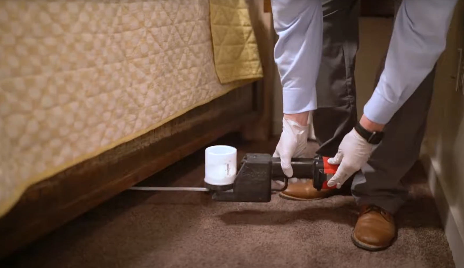 Technician inspecting and treating under a bed with specialized equipment — Pest Control Service in Napa.